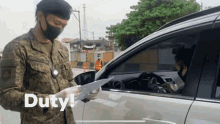 a man in a military uniform is standing next to a car holding a piece of paper with the word duty written on it