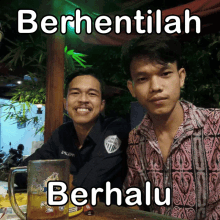 two men are sitting next to each other with the words berhentilah berhulu written on the bottom