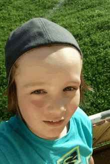 a young boy wearing a blue shirt and a gray hat