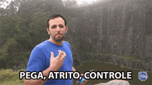 a man in a blue shirt stands in front of a cliff with the words pega atrito controle above him