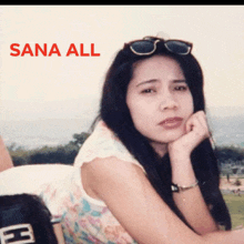 a woman wearing sunglasses sits with her hand on her chin and the words sana all above her