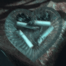 a heart shaped ashtray filled with cigarettes and a lighter