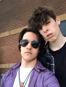 two young men wearing sunglasses pose for a photo