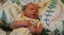 a baby is sleeping on a pillow with a floral blanket .