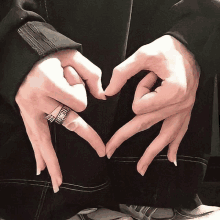 a person making a heart shape with their hands with rings on their fingers