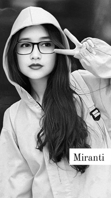 a black and white photo of a woman wearing glasses and a hoodie that says miranti on it