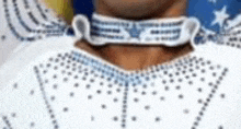 a close up of a person 's neck wearing a white shirt with rhinestones .