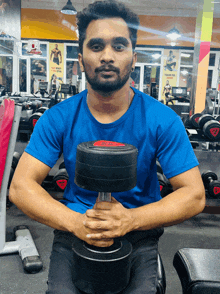 a man in a blue shirt is holding a black dumbbell