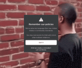 a man is standing in front of a brick wall with a warning message that says remember our policies