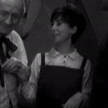a black and white photo of a man and a woman standing next to each other in a room .