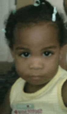 a close up of a little girl 's face with a yellow shirt on .