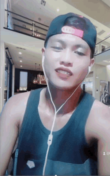 a man wearing a black tank top and a baseball cap with headphones on