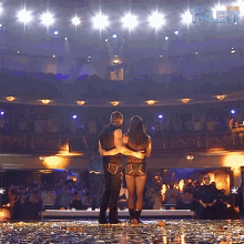 a man and a woman are hugging on a stage in front of a crowd with the word talent in the corner