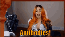 a woman with red hair is sitting in front of a microphone and says antibodies !