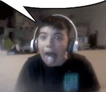 a young boy wearing headphones is sticking his tongue out in front of a speech bubble .