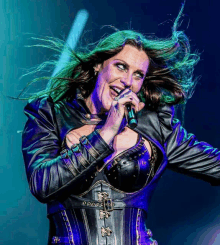 a woman singing into a microphone wearing a leather jacket