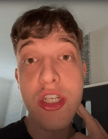 a close up of a man 's face with a red lip