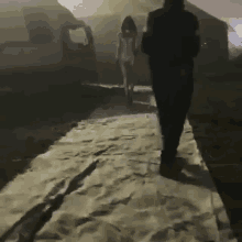 a man and a woman are walking down a sandy path in front of a plane .