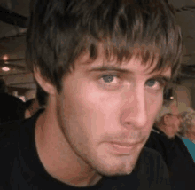 a close up of a man 's face wearing a black shirt .