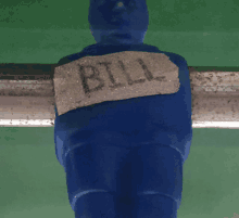 a blue figure with a piece of paper that says bill on the back