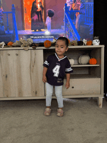 a little girl wearing a purple jersey with the number 4