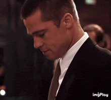 a close up of a man in a suit and tie looking down .