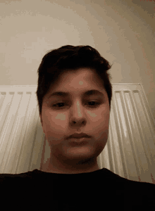 a close up of a young man 's face in front of a white radiator