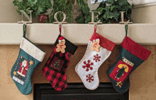 four christmas stockings are hanging on a mantle with the word noel behind them