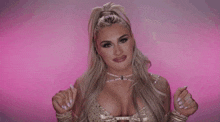 a woman in a very revealing outfit is dancing in front of a pink background and says toodles .