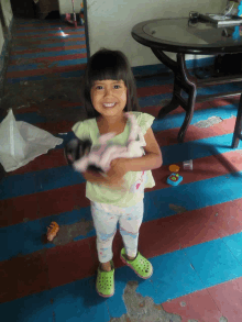 a little girl wearing green crocs holds a doll