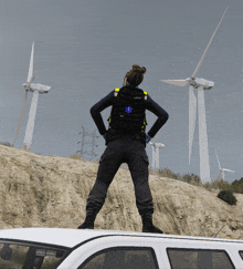 a person wearing a backpack with a blue star on it stands in front of windmills