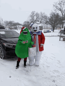 two people dressed in costumes are standing in the snow with a car in the background