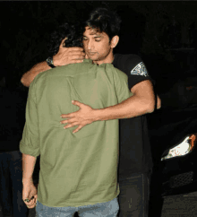 a man in a green shirt is hugging another man