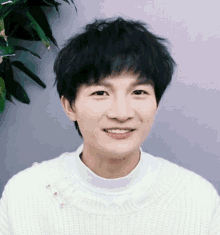 a young man wearing a white sweater is smiling