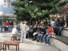 a group of people sitting on a ledge including a boy wearing a shirt that says ' aerie '