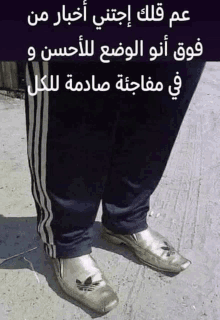 a person wearing a pair of adidas shoes with arabic writing on it