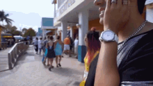 a man with a watch on his wrist stands in front of a building that says ' hotel ' on it