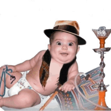 a baby wearing a hat and scarf is laying on a blanket next to a hookah