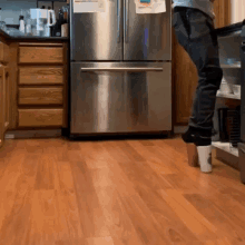 a person is standing in front of a stainless steel refrigerator in a kitchen