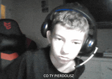 a boy wearing headphones and a microphone with the words co ty pierdolisz below him