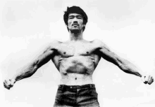 a man without a shirt is flexing his muscles in a black and white photo .