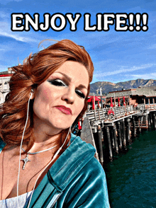 a woman wearing ear buds stands in front of a pier with the words enjoy life below her