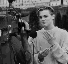 a black and white photo of a man being interviewed by a cameraman