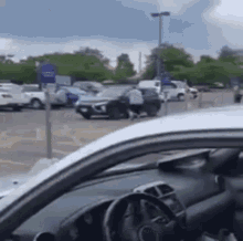 a man is standing next to a car in a parking lot while a police car is driving by .