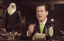 a man in a suit and tie with a bag of pistachios behind him