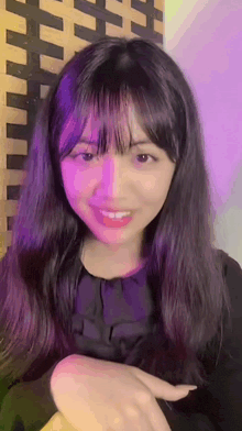 a young girl with long black hair and bangs is smiling .