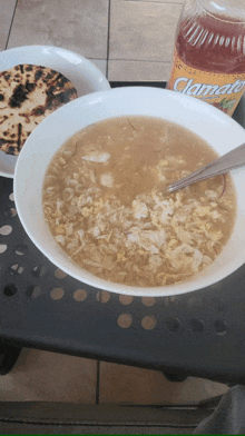 a bowl of soup sits next to a bottle of clamato