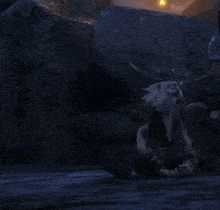 a cartoon character with horns is sitting on the ground in the dark