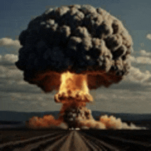 a large nuclear explosion is coming out of the ground in a field .