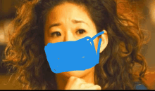 a woman with curly hair wearing a blue mask on her face